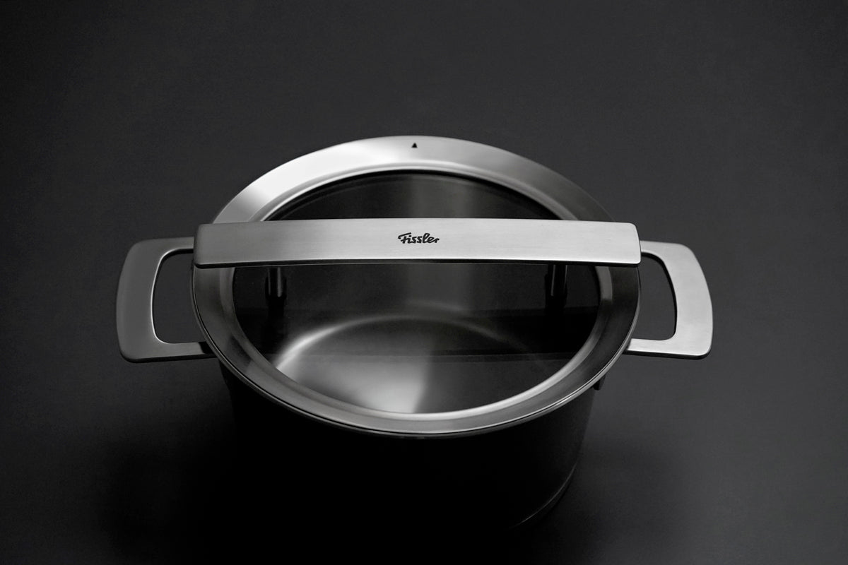Der Fissler Phi Collection Glasdeckel 20cm mit unserem ikonischen Logo auf dem Griff zeigt deutsche Präzision vor einem dunklen Hintergrund.