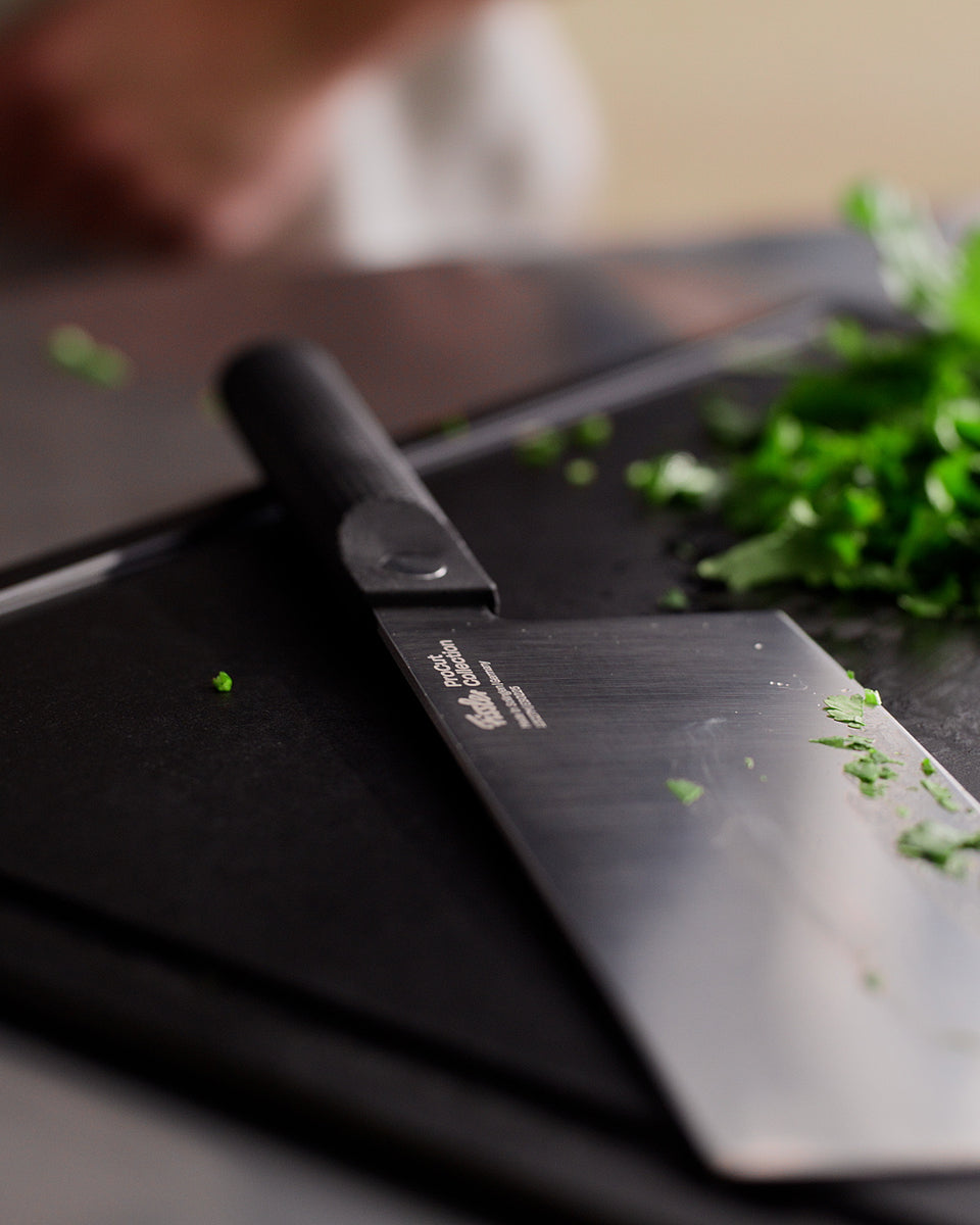 Fissler ProCut Chinese Chef's Knife 18cm-zeitloses Design, präzisionsgefertigt, auf Schneidebrett mit Kräutern und Knoblauch in der Nähe.