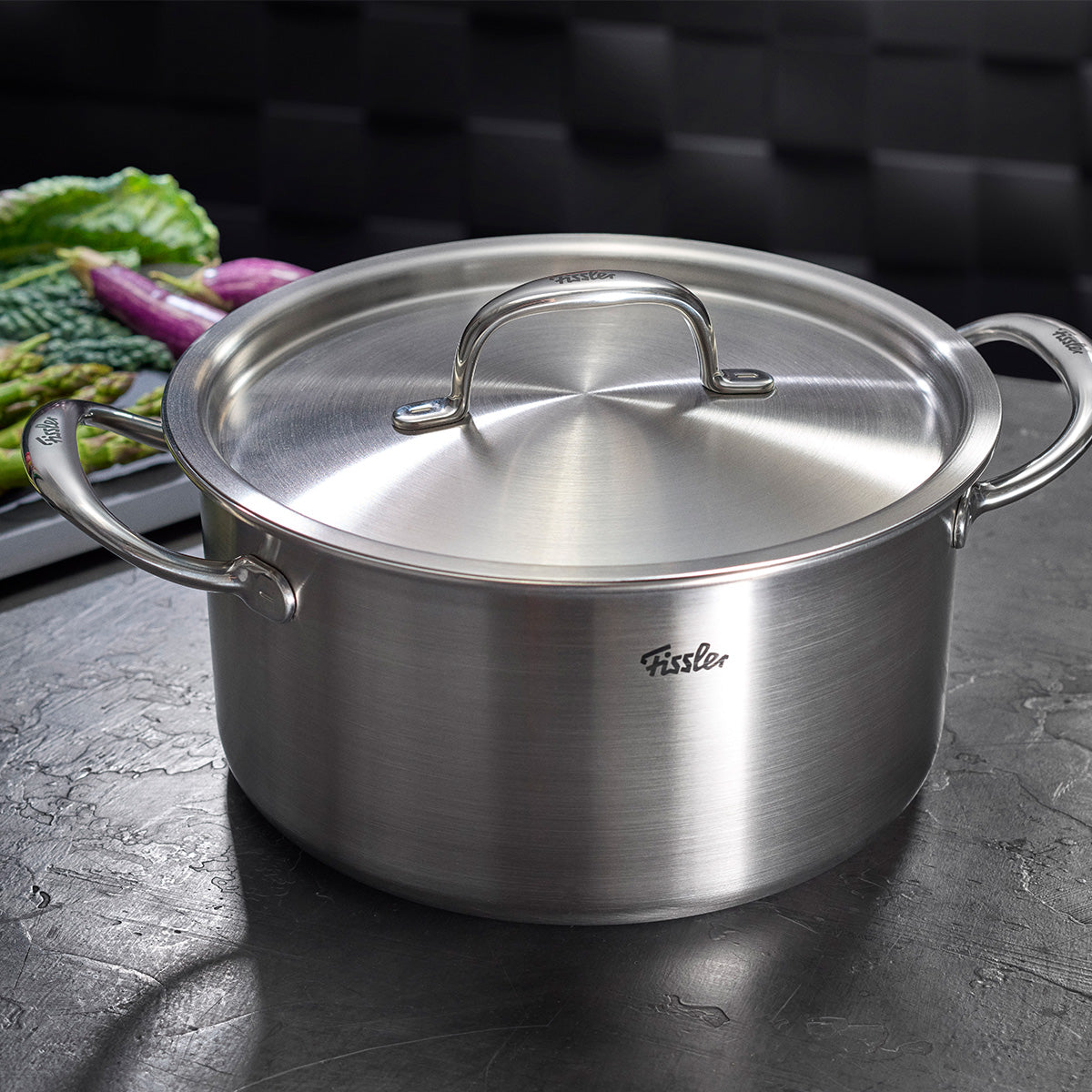 Fissler M5 Pro-Ply Kochtopf mit Metalldeckel aus recyceltem Edelstahl, modern & langlebig, auf dunkler Arbeitsfläche in Küche.