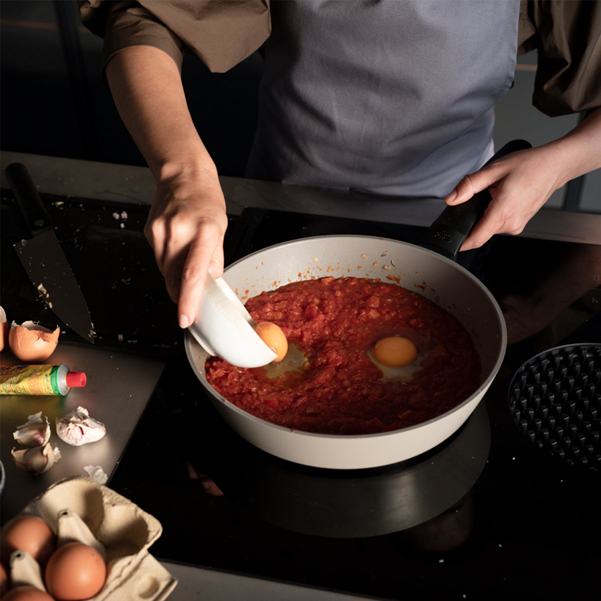 Experience precision cooking with Fissler Ceratal® Evo Comfort pans as eggs are cracked into tomato sauce, surrounded by fresh ingredients.