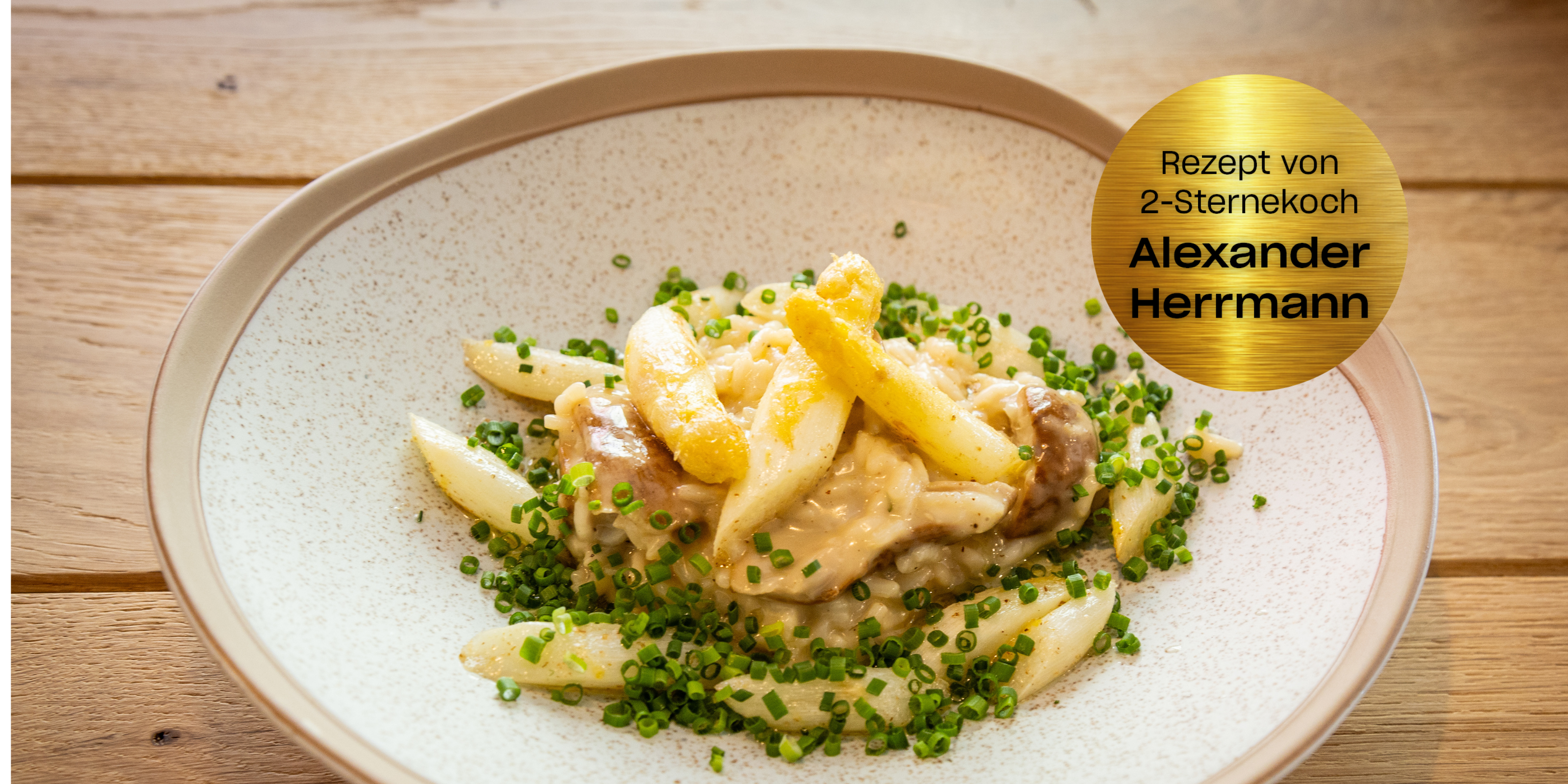 Eleganter weißer Spargel und Gnocchi in Sahnesoße, auf Holz in Fissler-Qualität angerichtet. Goldplakette: Alexander Herrmann.